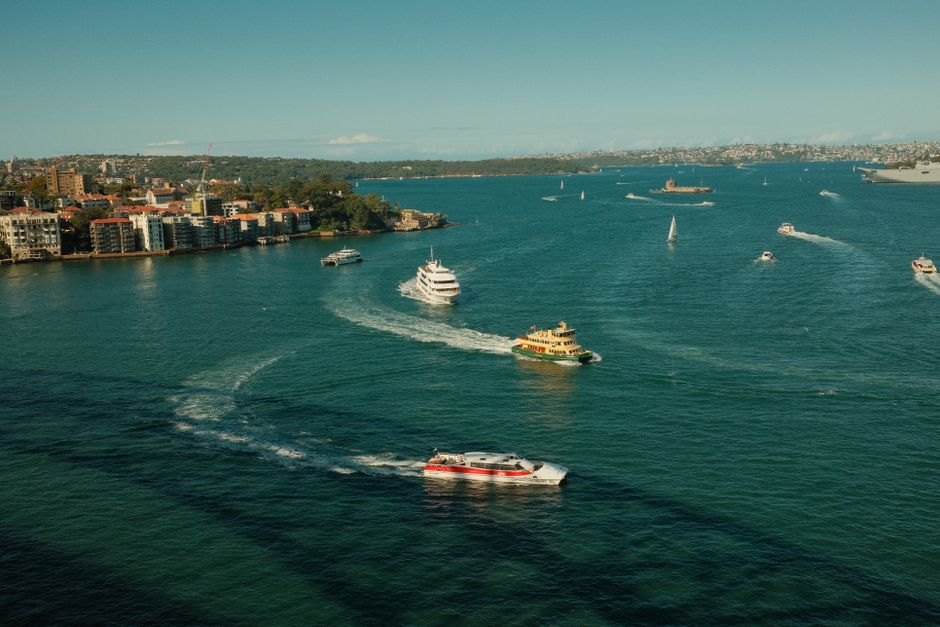 Boats navigate the bustling waters of Sydney Harbour on a sunny day.