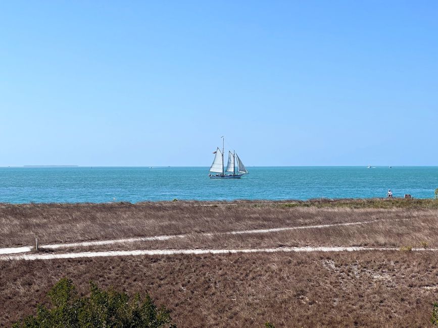 Scenic view of a sailboat on turquoise ocean near Key West, under a clear summer sky.