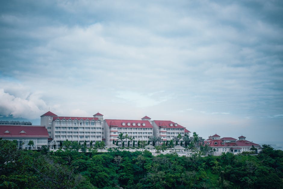 Wide view of a stylish hotel with red roofs amidst lush greenery and cloudy sky in Taiwan.