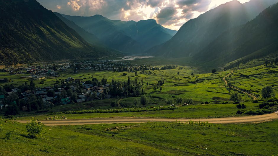 Breathtaking view of a lush green valley nestled between mountains under a dramatic sunset sky.