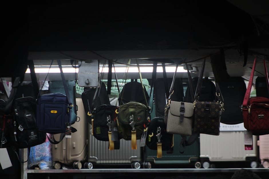 Colorful bags and luggage hang on display in a dimly lit market setting.