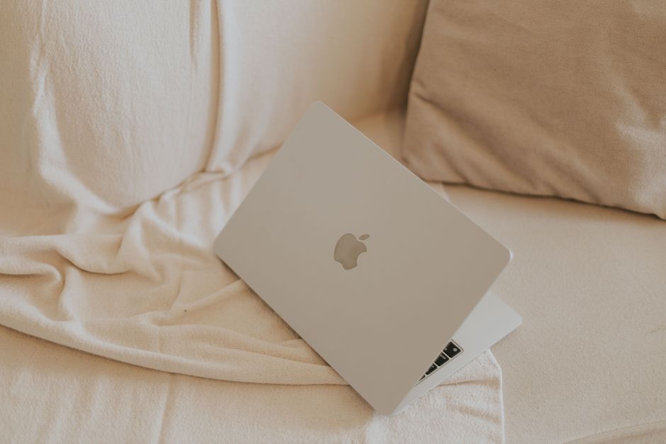 A sleek silver laptop on a beige sofa, perfect for minimalist home office inspiration.