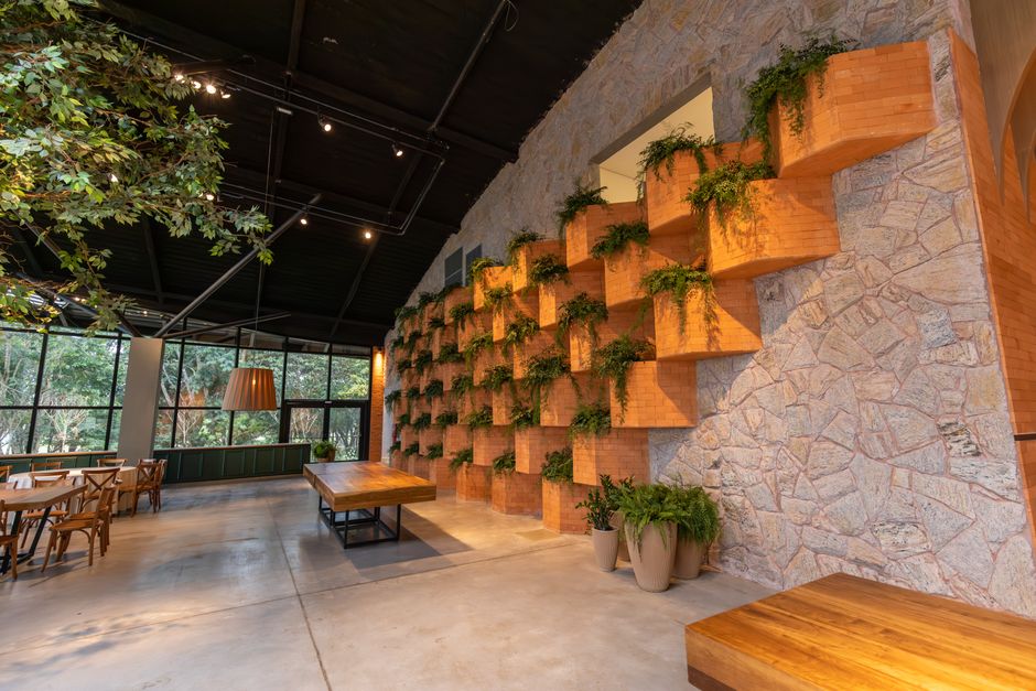 A spacious restaurant interior featuring brick wall design and indoor plants for a natural ambiance.