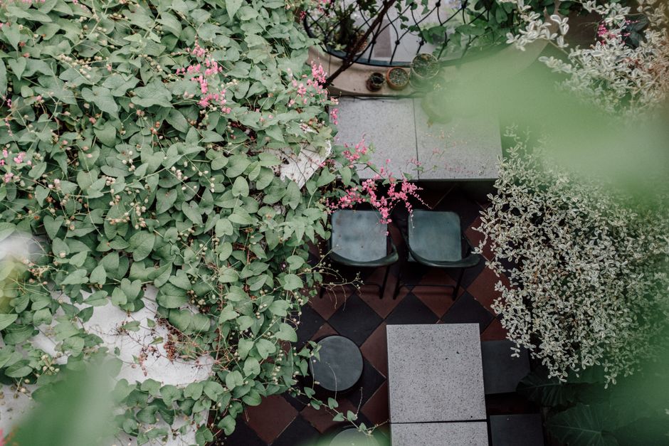 Overhead view of a serene garden with lush greenery and pink flowers accentuating seating area.