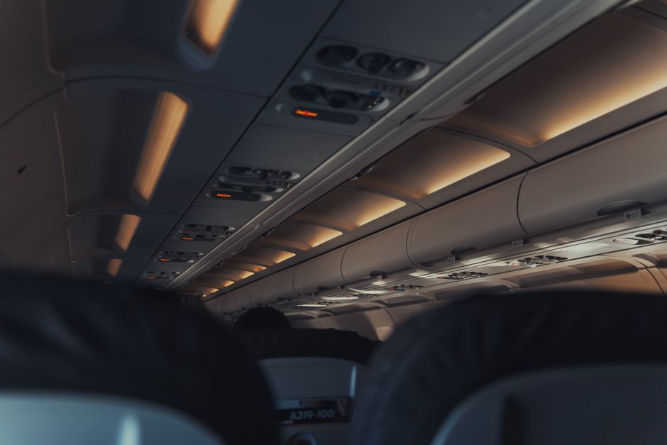 Interior view of a commercial airplane cabin focusing on overhead lights and seats.