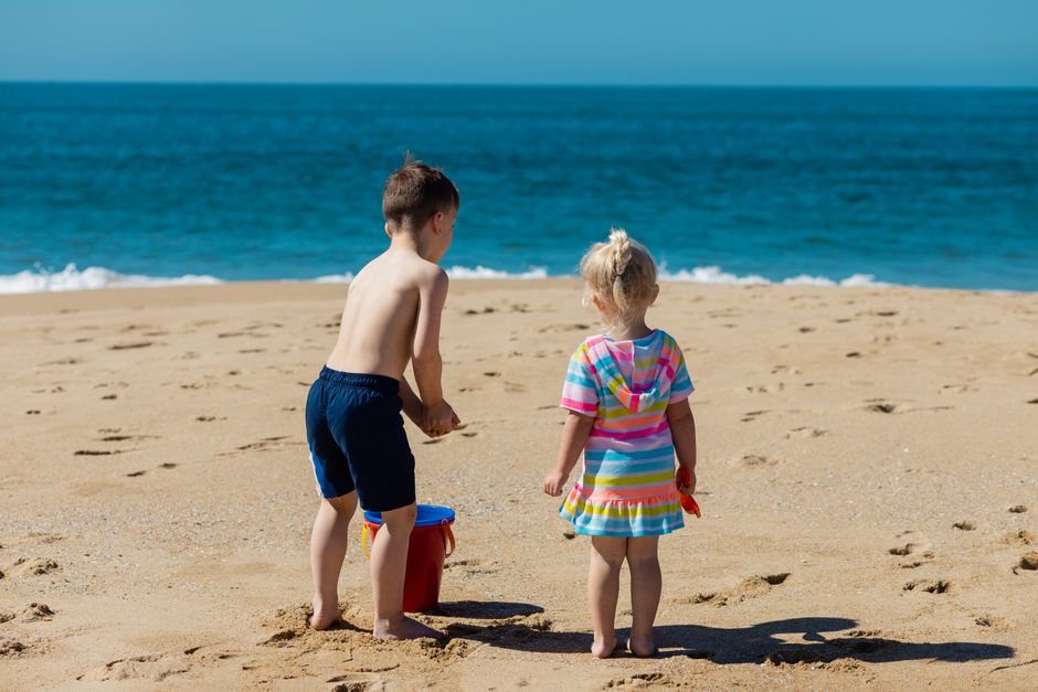 A boy and girl enjoying a day at the beach, playing near the ocean shore.