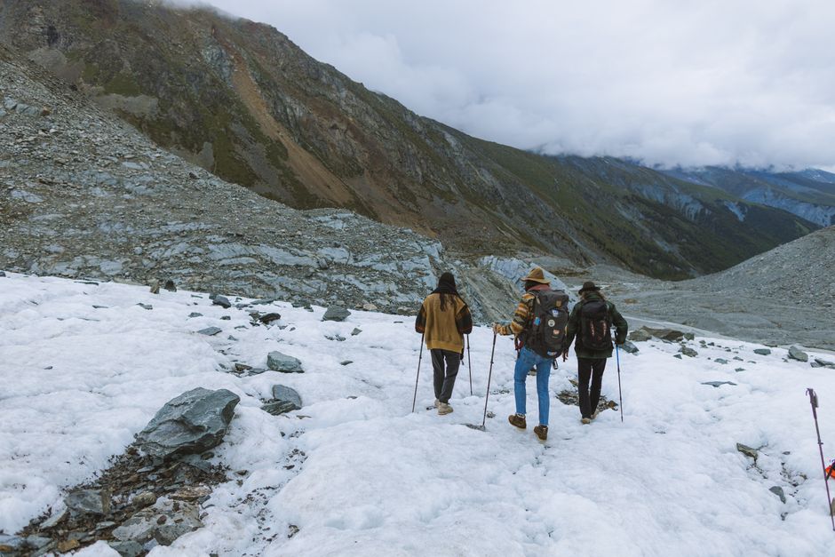 Three hikers traverse a snow-covered mountain in winter, showcasing adventure.