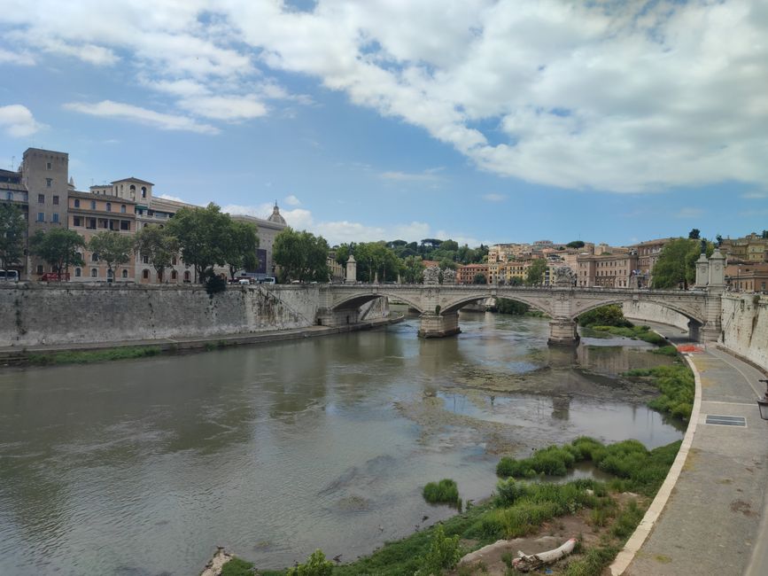 A serene capture of the historic urban bridge spanning a tranquil river under a cloudy sky.