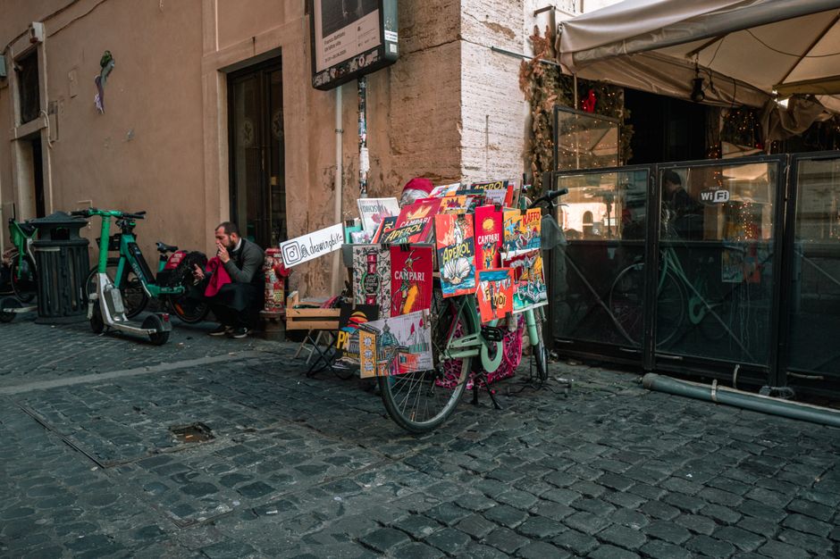 A vibrant street scene in Rome featuring a bicycle covered in colorful posters.