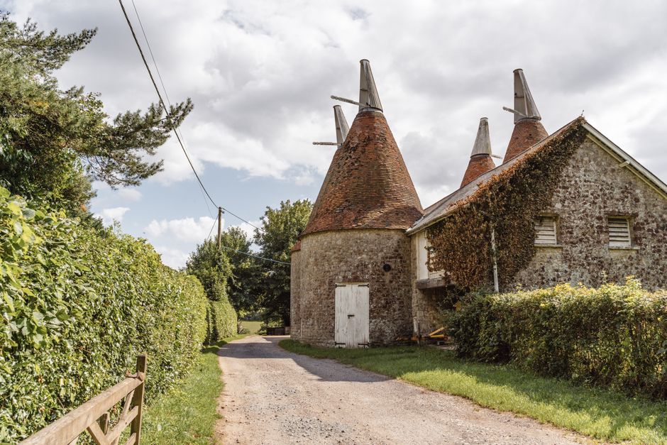 Shabby stone buildings with towers located near rural path with green bushes in suburban a