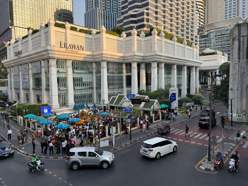 Busy intersection with Erawan Shrine and surrounding hustle in Bangkok.