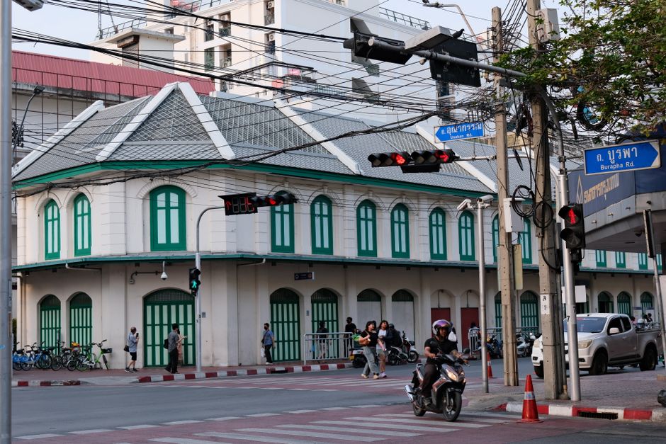 A bustling intersection in Bangkok featuring colonial architecture and vibrant street life.