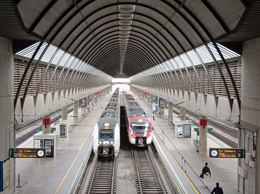 Aerial view of a bustling train station in Seville with two trains ready for departure.