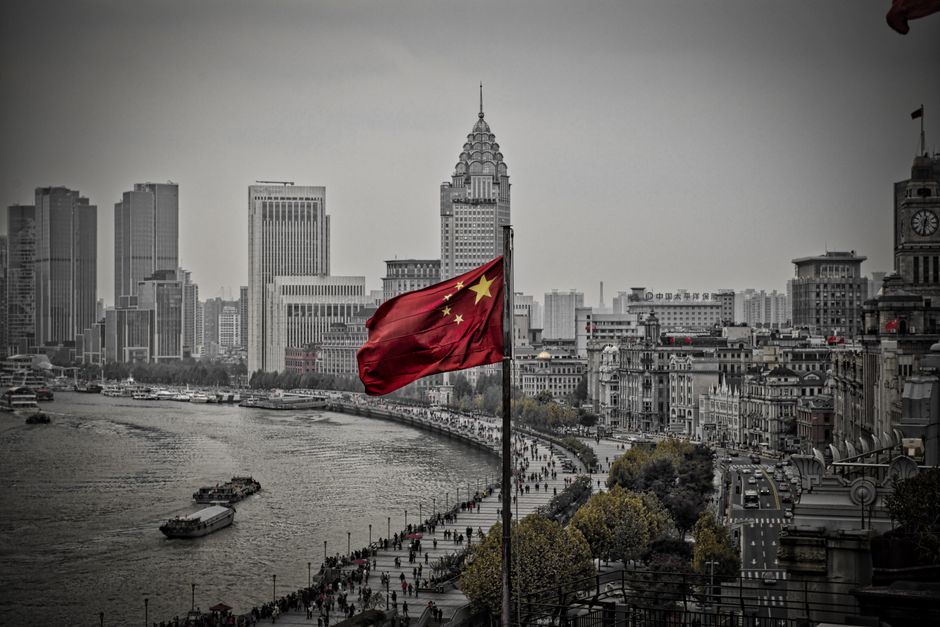 A striking view of the Chinese flag flying over the iconic skyline of Shanghai, showcasing the urban cityscape.