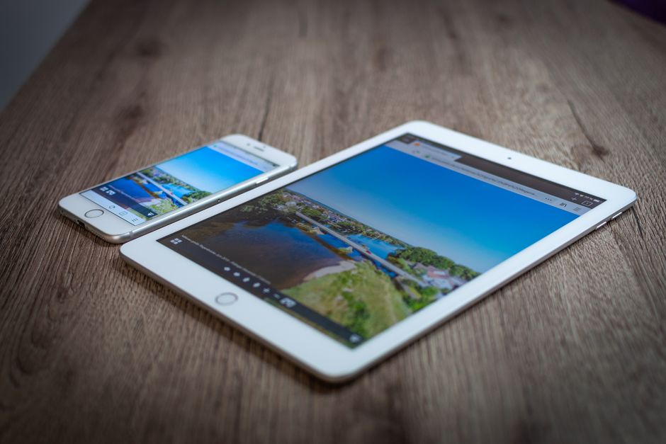 iPad and iPhone showing a scenic landscape on a wooden table, highlighting portability and technology.