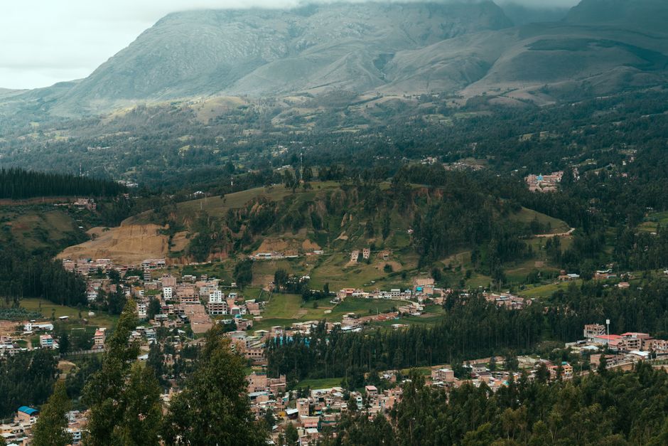 A beautiful aerial view of a mountainous village landscape with lush greenery and distant peaks.