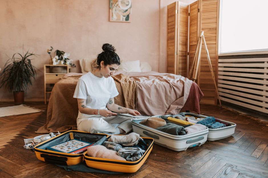 A woman organizes luggage in a stylish bedroom, carrying wanderlust vibes.